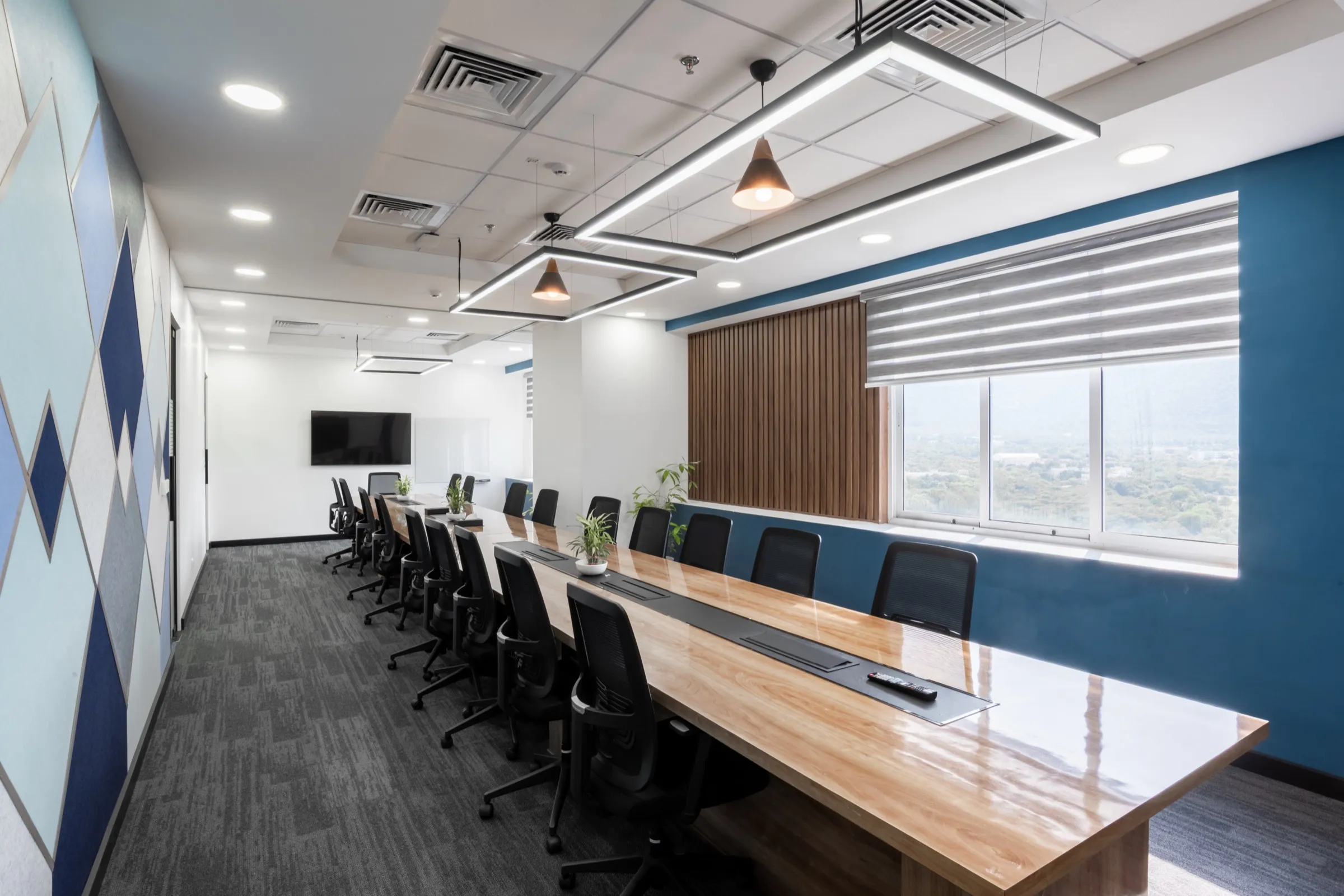 Long boardroom table with a blue feature wall, timber panelling and window blinds
