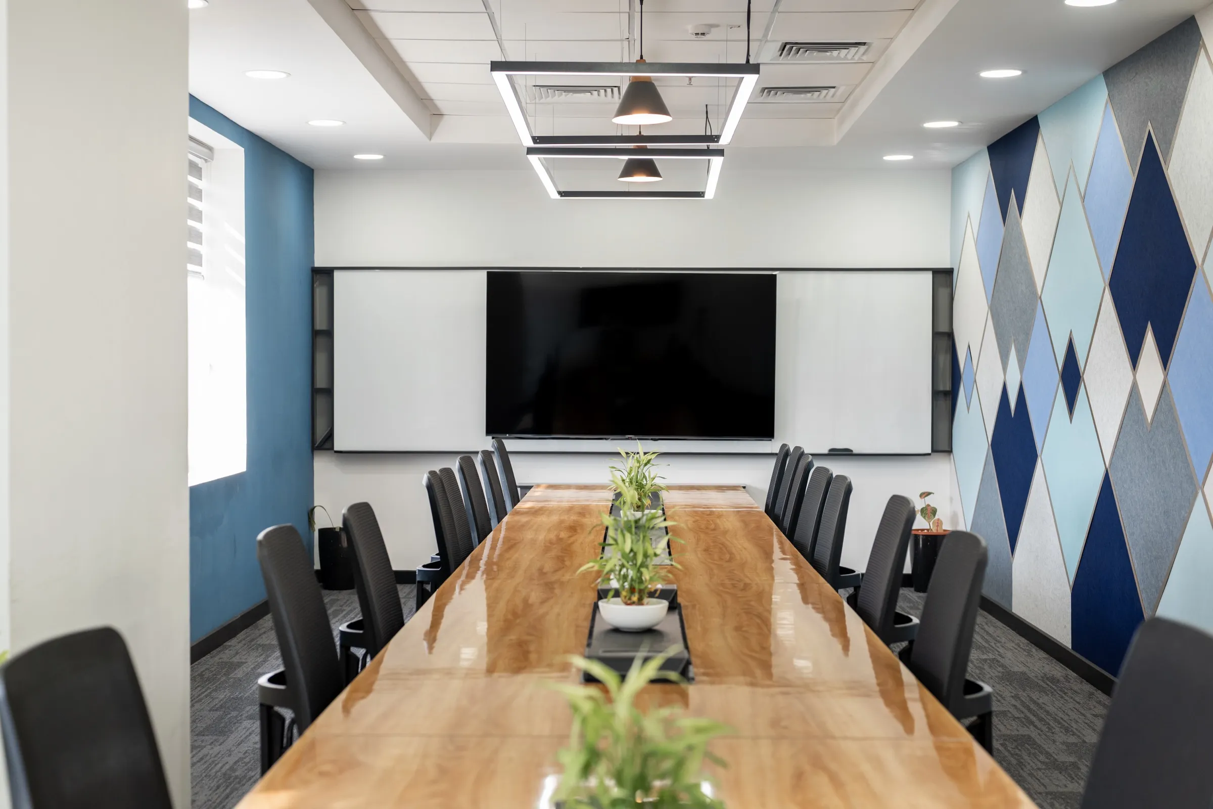 Conference room with a wall-mounted screen and a blue geometric accent wall